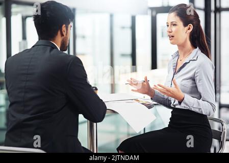 Ha una chiara visione d'affari: Due uomini d'affari che parlano insieme mentre si siedono al tavolo in un ufficio. Foto Stock