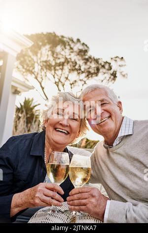 Una felice e rilassante pensione. Una coppia anziana felice brinda con il vino in un piacevole pomeriggio fuori. Foto Stock