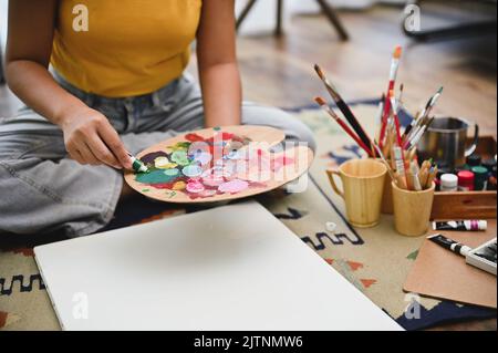 Attraente giovane artista asiatico disegno e pittura di colore acrilico su un poster bianco. Immagine ritagliata Foto Stock