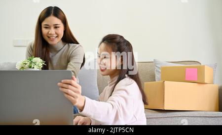 Due giovani donne asiatiche startup piccoli imprenditori o freelance che utilizzano computer portatile per controllare i loro ordini di vendita online. E-commerce busines Foto Stock