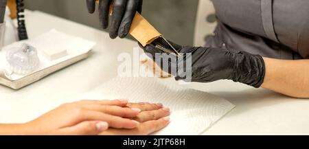 Il maestro di manicure prende gli attrezzi di manicure da una busta di kraft in un salone delle unghie Foto Stock