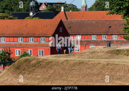 Copenaghen, Danimarca. Agosto 13, 2022. Persone che camminano in cima ai bastioni di Kastellet, con caserme rosse sullo sfondo Foto Stock