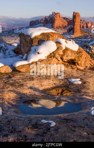 Riflessioni in piscine di neve scioglienti acqua una tempesta d'inverno. Vicino a Balanced Rock nel parco nazionale di Arches, Moab, Utah. Foto Stock