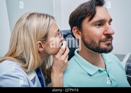 Medico di controllo dell'orecchio dell'uomo adulto che usa otoscopio o auriscopio presso il centro medico Foto Stock