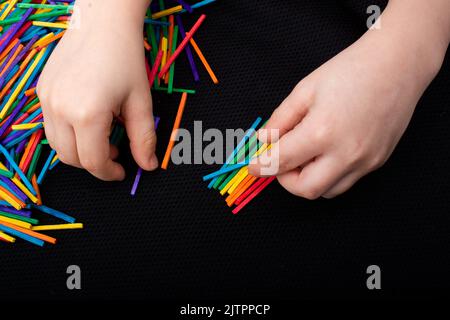 Kid a giocare con i colori dei bastoncini di legno per la creatività su sfondo bianco Foto Stock