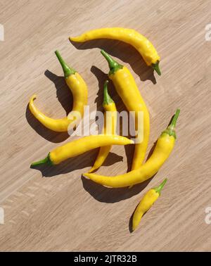 Una pila di peperoni giallo brillante Cayenne su uno sfondo di legno chiaro Foto Stock