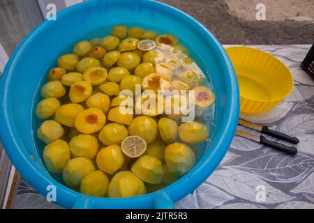 Immagine di una bacinella con pesche tagliate e limone. Preparazione di pesche sciroppate in vasetti. Foto Stock