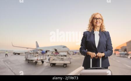 Donna d'affari con una valigia in posa in aeroporto Foto Stock