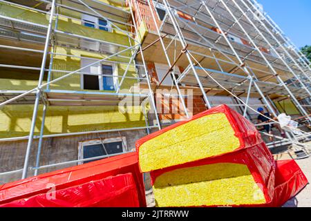 Imballaggio di materiale di isolamento termico, lana di pietra avvolta in foglio è in attesa di essere installato sulle pareti dell'edificio residenziale in costruzione Foto Stock