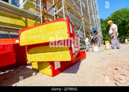 Imballaggio di materiale di isolamento termico, lana di pietra avvolta in foglio è in attesa di essere installato sulle pareti dell'edificio residenziale in costruzione Foto Stock