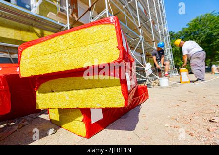 Imballaggio di materiale di isolamento termico, lana di pietra avvolta in foglio è in attesa di essere installato sulle pareti dell'edificio residenziale in costruzione Foto Stock