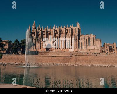 La bellissima Cattedrale di Palma di Maiorca con una fontana di fronte a un cielo blu Foto Stock