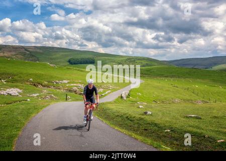 Ciclisti in bicicletta lungo una corsia di campagna sopra Malham Moor in una giornata di sole estate, Yorkshire Dales National Park, paesaggi del Regno Unito Foto Stock