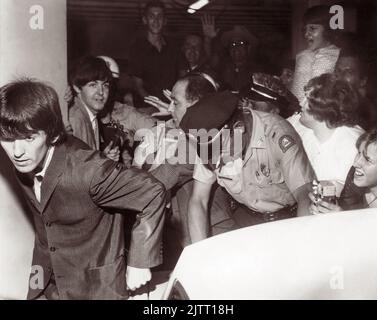 I Beatles (George Harrison in primo piano e Paul McCartney dietro di lui) lasciando il George Washington Hotel con la polizia cercando di controllare i fan pressanti mentre la band si dirigeva per il loro concerto Gator Bowl a Jacksonville, Florida, il 11 settembre 1964. (USA) Foto Stock