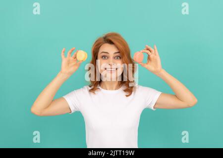 signora sorpresa tenere dolce macaron biscotto francese su sfondo blu Foto Stock