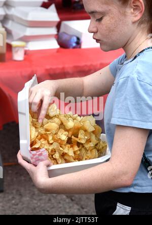 Una giovane ragazza mangia un servizio di patatine fritte ricce acquistate da un venditore di cibo in un festival a Santa Fe, New Mexico. Foto Stock