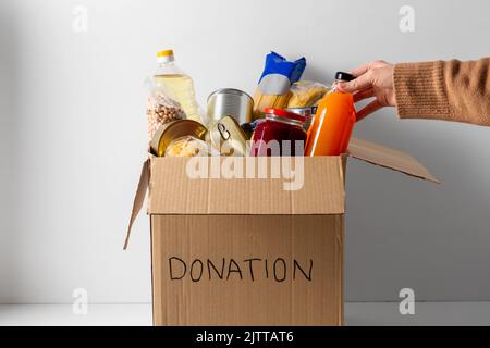 primo piano del cibo in scatola di donazione e a mano Foto Stock