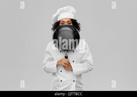 chef femminile che si sbirciava da dietro la padella Foto Stock
