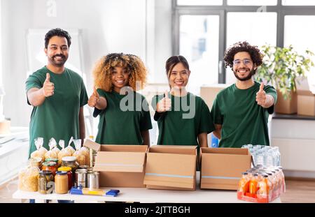 volontari con donazione di cibo che mostra pollici in su Foto Stock