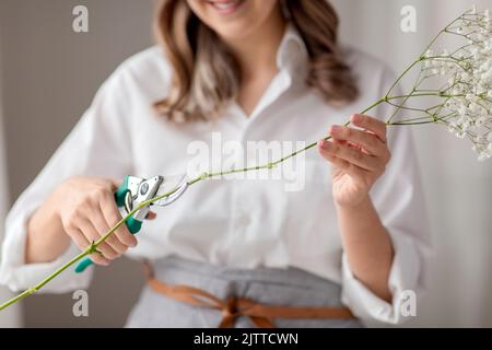 donna che taglia il gambo del fiore con cesoie potanti Foto Stock