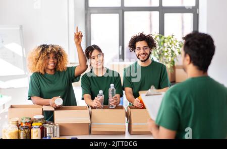 volontari felici che imballano il cibo in scatole di donazione Foto Stock