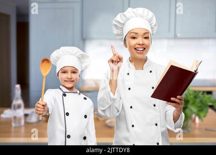 chef femminile con libro di cuoco e ragazza in cucina Foto Stock