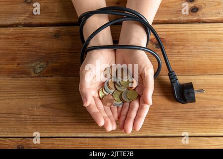 primo piano delle mani legate con spina che tiene monete Foto Stock