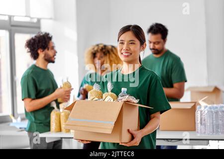 volontari felici che imballano il cibo in scatole di donazione Foto Stock