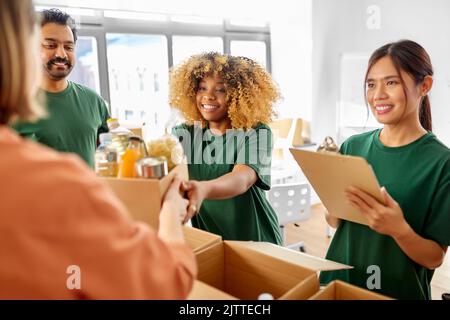 volontari felici che imballano il cibo in scatole di donazione Foto Stock