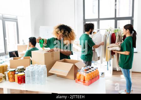 volontari felici che imballano il cibo in scatole di donazione Foto Stock