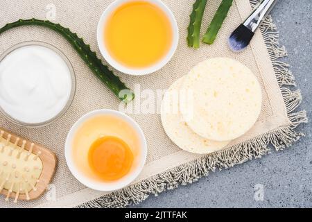 Rendere i capelli e la maschera di faccia a casa. Cosmetici fatti in casa con ingredienti naturali - tuorlo d'uovo, miele alle erbe, aloe vera e yogurt greco. Cura naturale della pelle Foto Stock