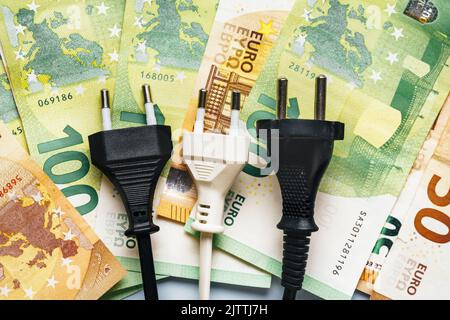 Spina elettrica accanto alle banconote in euro che mostra l'aumento drastico dei costi per l'elettricità. Il concetto di crisi energetica in Europa. Vista dall'alto. Primo piano Foto Stock