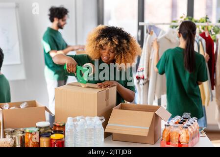 volontari felici che imballano il cibo in scatole di donazione Foto Stock