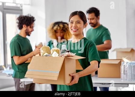 volontari felici che imballano il cibo in scatole di donazione Foto Stock