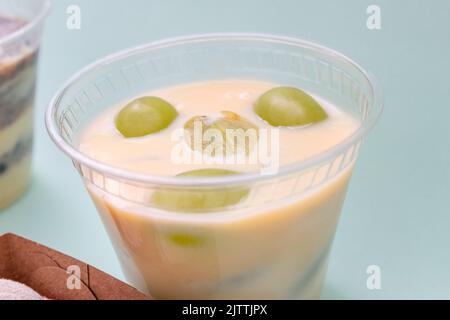 latte condensato dolce con uva in un bicchiere. Foto Stock