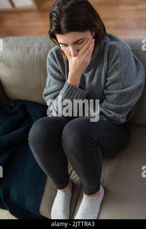 donna stressata seduta sul divano a casa Foto Stock