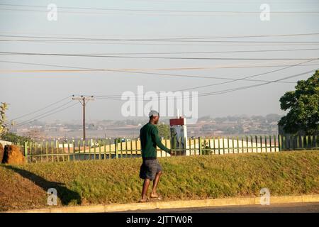 Un uomo è visto a piedi in un centro commerciale a Lilongwe dove le linee elettriche si incrociano. Malawi. Foto Stock