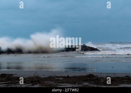 Grandi onde si schiantano contro la frangiflutti della spiaggia di El Puerto de Sagunto in una giornata tempestosa sotto un cielo drammatico. Porto di Sagunt - Valencia Foto Stock