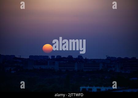 Tramonto sole e città con disco arancione sopra sobborgo di Parigi Foto Stock
