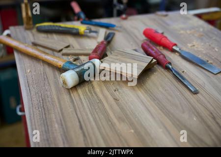 Vari utensili per la lavorazione del legno e pezzi di legno giacenti su una superficie di lavoro in un'antica officina di falegname. Russikon, Zurigo Oberland, Svizzera Foto Stock