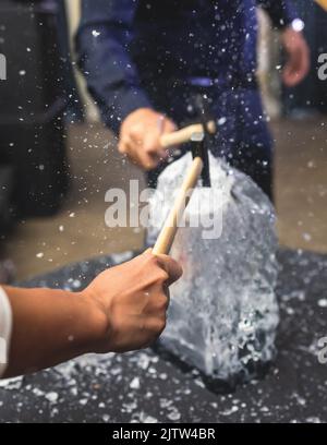 Processo di rottura del ghiaccio con martello e raccogli ghiaccio, gruppo di persone che distruggono il cubo di ghiaccio frantumato, concetto di successo del lavoro di squadra, concetto di partenza pari Foto Stock