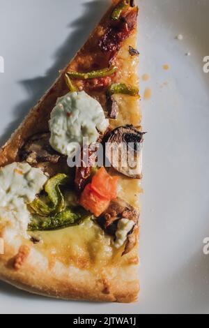 formaggio di capra pomodoro essiccato peperone verde pizza funghi su piatto bianco Foto Stock