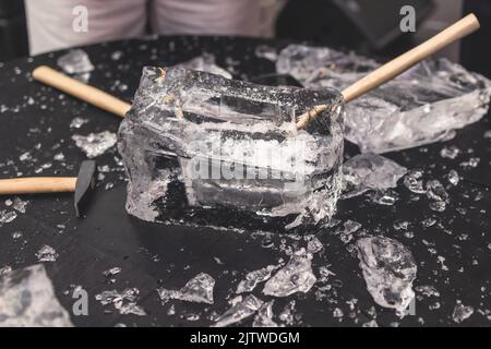 Processo di rottura del ghiaccio con martello e raccogli ghiaccio, gruppo di persone che distruggono il cubo di ghiaccio frantumato, concetto di successo del lavoro di squadra, concetto di partenza pari Foto Stock