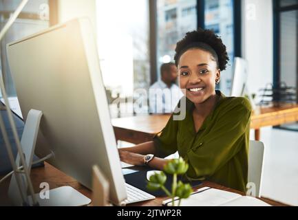 Mi piace quello che faccio. Ritratto ritagliato di una donna d'affari che lavora sul suo computer in ufficio. Foto Stock