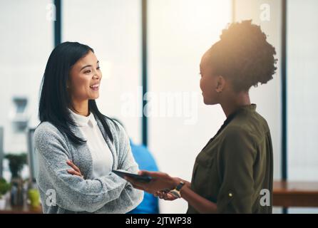 Condividono la stessa ambizione di avere successo: Due giovani creativi che discutono in un ufficio. Foto Stock