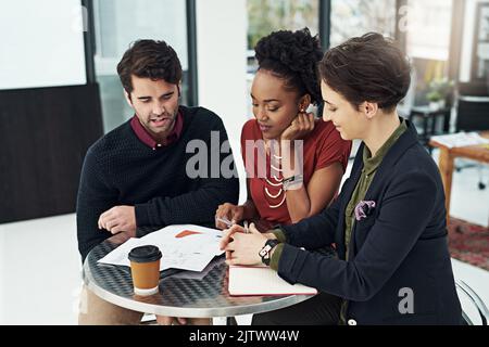 Sulla scia di un'idea rivoluzionaria. Un gruppo di uomini d'affari si riunisce intorno ad un piccolo tavolo nel loro ufficio. Foto Stock