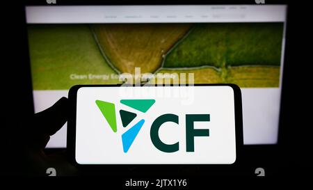 Persona che detiene uno smartphone con il logo della società statunitense di fertilizzanti CF Industries Holdings Inc. Sullo schermo di fronte al sito Web. Messa a fuoco sul display del telefono. Foto Stock