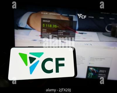 Persona che tiene il cellulare con il logo della società statunitense di fertilizzanti CF Industries Holdings Inc. Sullo schermo di fronte alla pagina web. Messa a fuoco sul display del telefono. Foto Stock