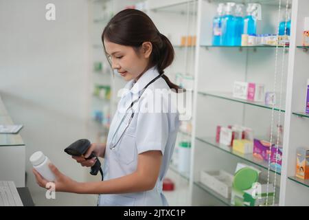 Concetto di medicina e salute, farmacista femminile scansione del codice a barre del prodotto della medicina nel registratore di cassa. Foto Stock