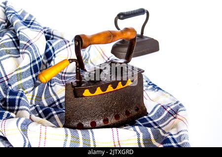 Immagine di vecchi ferri da stiro a carbone con una camicia da stirare. Vecchi ricordi e costumi Foto Stock
